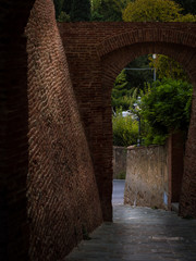 A narrow passage between two red brick walls in an old medieval Italian city with a beautiful view