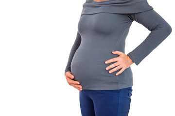 A pregnant woman stands, using the right hand to gently rub the abdomen and using the left hand to lay the waist on a beautiful white background, Health care concept.