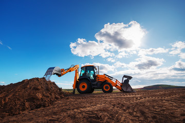 Wheel loader excavator with field background during earthmoving work, construction building