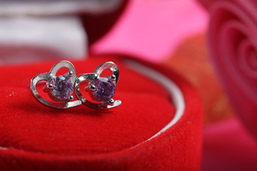 Close ups shot of white golden heart shaped ear stud with purple crystals gem