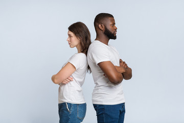 Multiracial couple standing back to back, ignoring each other after argue