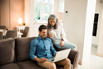 Obraz premium Happy adult couple resting on sofa at home