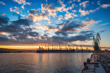 Naklejka premium Colorful sunset over sea port and industrial cranes, Varna, Bulgaria.