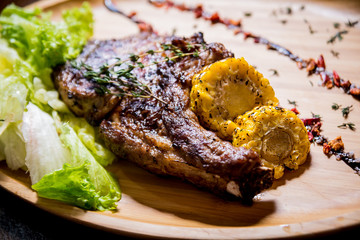 Pork grilled ribs with corn and salad on a wooden board. 