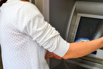 A woman withdraws cash through an ATM using a plastic card.