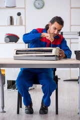 Young male contractor repairing air-conditioner at workshop