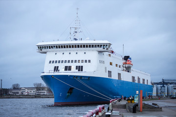 Big blue cargo ship docked at small baltic sea port.