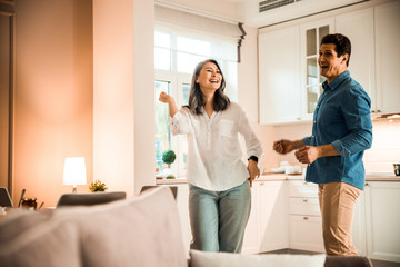 Fototapeta premium Happy woman dancing with her husband in the kitchen