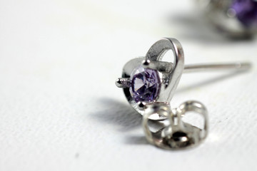 Close ups shot of white golden heart shaped ear stud with purple crystals gem