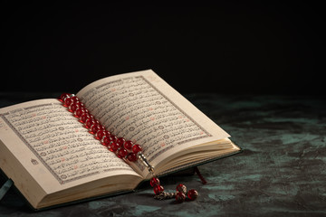 Islamic concept: The holy Quran and Tasbih (rosary beads) on dark background