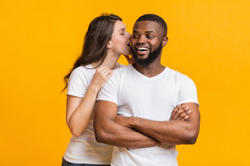 Obraz premium Romantic woman whispering about love into her black boyfriend's ear