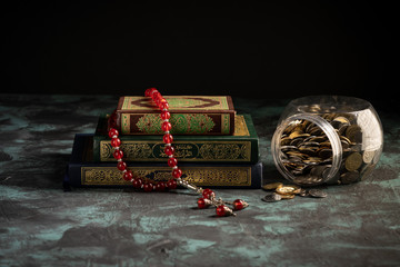 Zakat concept: Quran and tasbih with jar full of coins