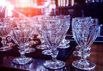 Wine and martini glasses in shelf above a bar rack in restaurant.