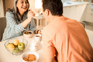 Happy pretty lady feeding her husband at home
