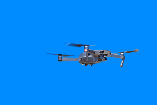 Modern drone with camera flying on a clear blue sky