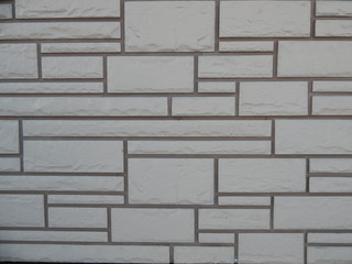 fragment of the exterior wall of the building with textured geometric cladding and dark seams