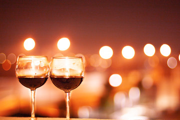 Two glasses of wine on a night city lights background. Violet shades.