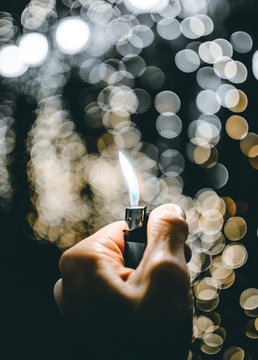 Close-Up Of Hand Holding Cigarette Lighter With Flame