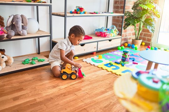 Beautiful african american toddler playing with tractor toy at kindergarten
