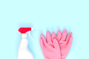 Detergents, cleaning accessories, pink rubber gloves on a blue background. Cleaning service concept. Top view, flat lay. Copy space.
