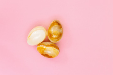 Decorative Easter eggs made from Natural gemstone onyx. Trendy spring holiday greeting card. Minimal flat lay pink  background.