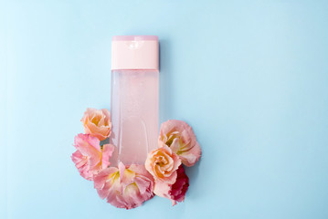 Pink bottle women's perfume with spring flowers on blue background with a copy space