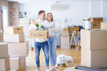 Fototapeta premium Young beautiful couple with dog moving cardboard boxes at new home