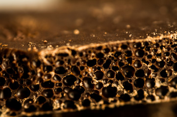 Black porous chocolate bubbles. Black porous chocolate on a white label close-up.