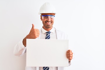 Young chemist man wearing security helmet holding signboard over isolated background happy with big smile doing ok sign, thumb up with fingers, excellent sign