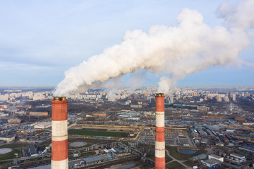 power plant pipes and cooling towers on the background of the panorama of the winter city against...