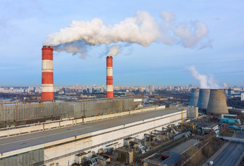 Obraz premium power plant pipes and cooling towers on the background of the panorama of the winter city against blue sky