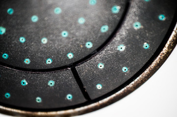 Close up of an old dirty shower with limescale. Bad water with deposits of salt and lime leaves a residue on the surface of the shower holes.