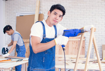 A carpenter is making a hold on wood by using a drill