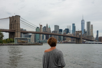 Woman tourist enjoying view of Brooklyn Bridge and Manhattan skyscrapers