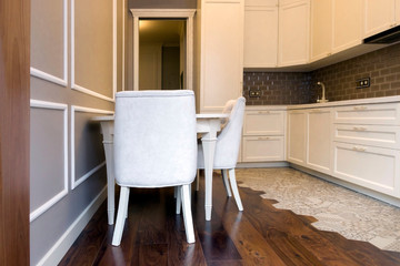 Facade of a white, wooden kitchen with a table and chairs. Scandinavian style kitchen design