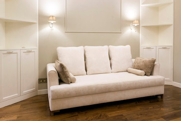 White sofa in a new, bright living room after repair. Laconic interior design