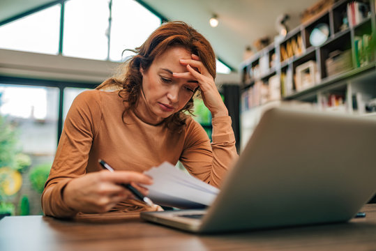 Portrait Of A Stressed Woman Looking At Financial Bills, Close-up.