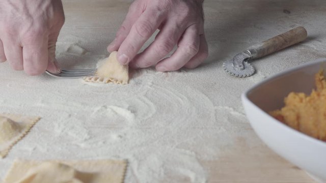 Closeup process making ravioli vegan homemade pasta. Chef cook closes with a fork 'tortelli di zucca', traditional italian pasta, husband cooking food on kitchen