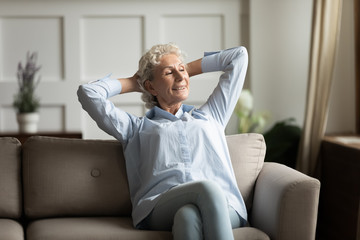 Peaceful middle aged calm woman relaxing on cozy sofa.