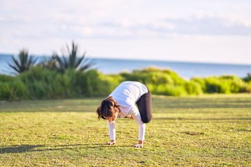 Young beautiful sportwoman practicing yoga. Coach teaching crow pose at park