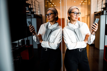Stylish businesswoman with smartphone in office stock photo