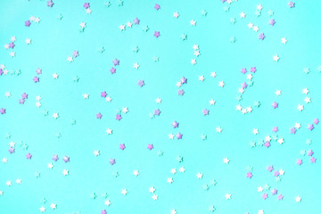 Little stars confetti on turquoise background. Holiday concept.