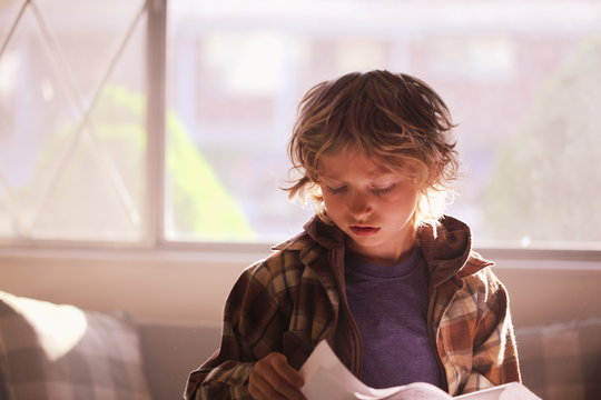 Boy Reading Paper At Home