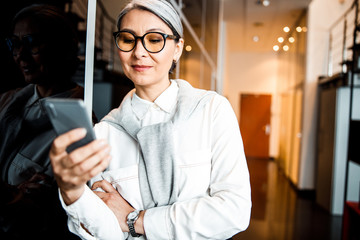 Joyful boss with smartphone in office stock photo