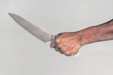 African man hold knife - aggression. Big kitchen knife in man hand. Large kitchen knife in a man's hand. Hand of african man holding a knife isolated on a gray background.