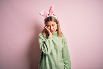 Young beautiful woman wearing easter rabbit ears standing over isolated pink background thinking looking tired and bored with depression problems with crossed arms.