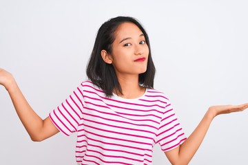 Young chinese woman wearing striped t-shirt standing over isolated white background clueless and...