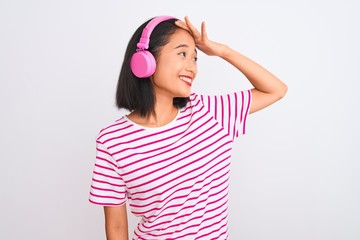Beautiful chinese woman listening to music using headphones over isolated white background stressed with hand on head, shocked with shame and surprise face, angry and frustrated. Fear and upset