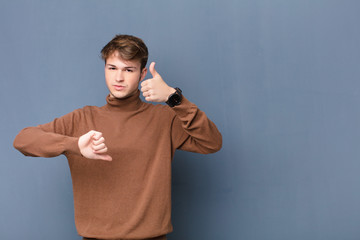 young blonde man feeling confused, clueless and unsure, weighting the good and bad in different...