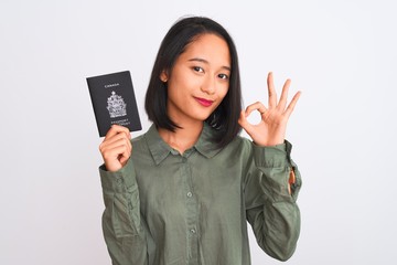 Beautiful chinese woman holding Canada Canadian passport over isolated white background doing ok...